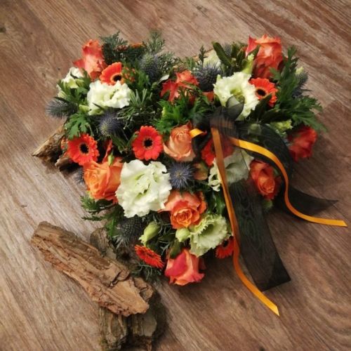 Blumengesteck in Herzform mit orangen und weißen Blumen